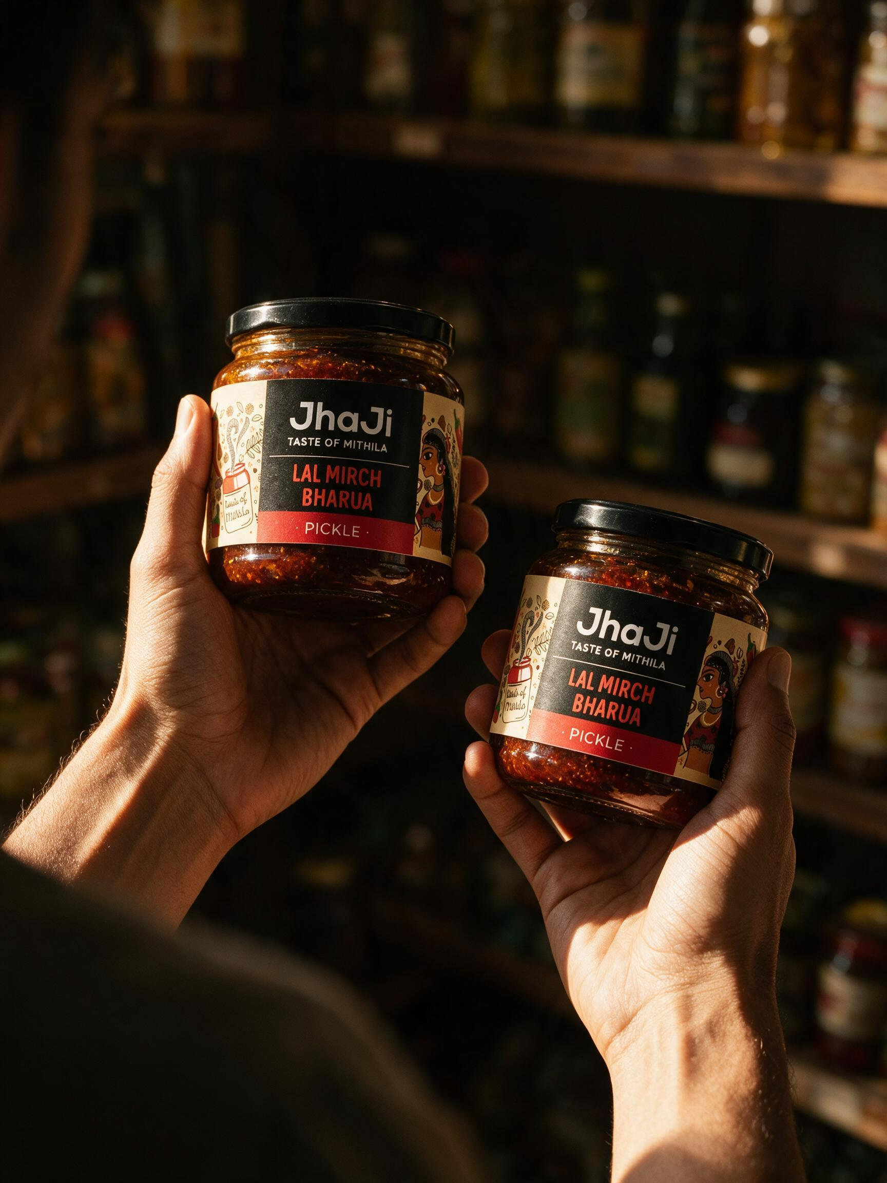 Two hands holding product jars in a warm dimly lit artisan grocery store