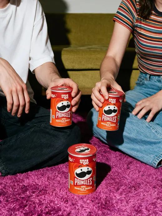 Gen-Z lifestyle product ad with two people sitting on a shag rug in front of a retro sofa